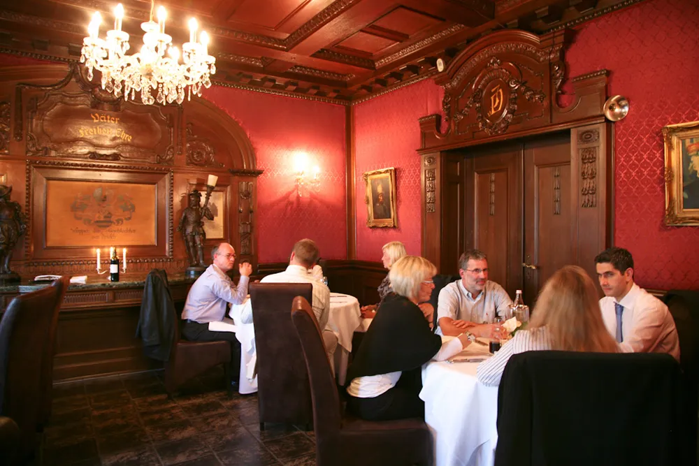 Lange, festlich gedeckte Tafel vor der Holzvertäfelung